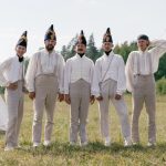 A group of soldiers in historical uniforms standing in a field beside a tent.