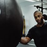 Boxer practicing punches on a heavy bag in a gym environment.